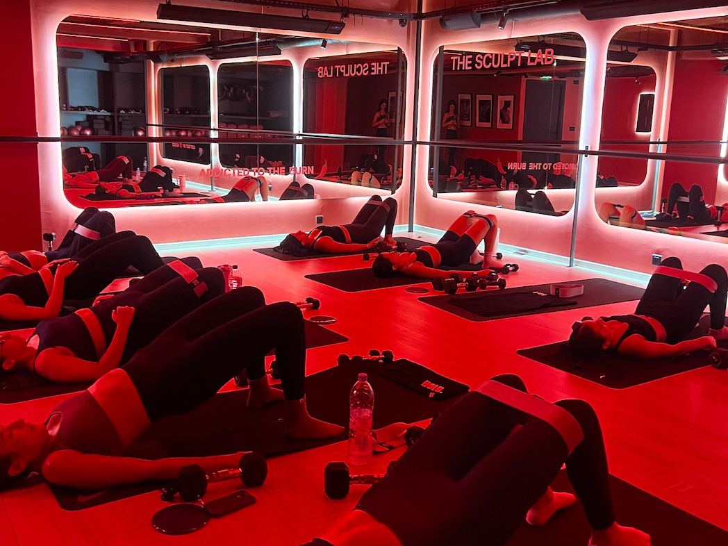 Cours de Pilates au sol dans The Sculpt Lab, salle chauffée à l'éclairage rouge